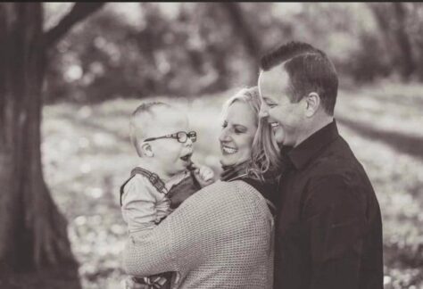 Tim McNutt smiling with his wife Amber and their son Elijah, honored by Helping One Guy for his strength and devotion.