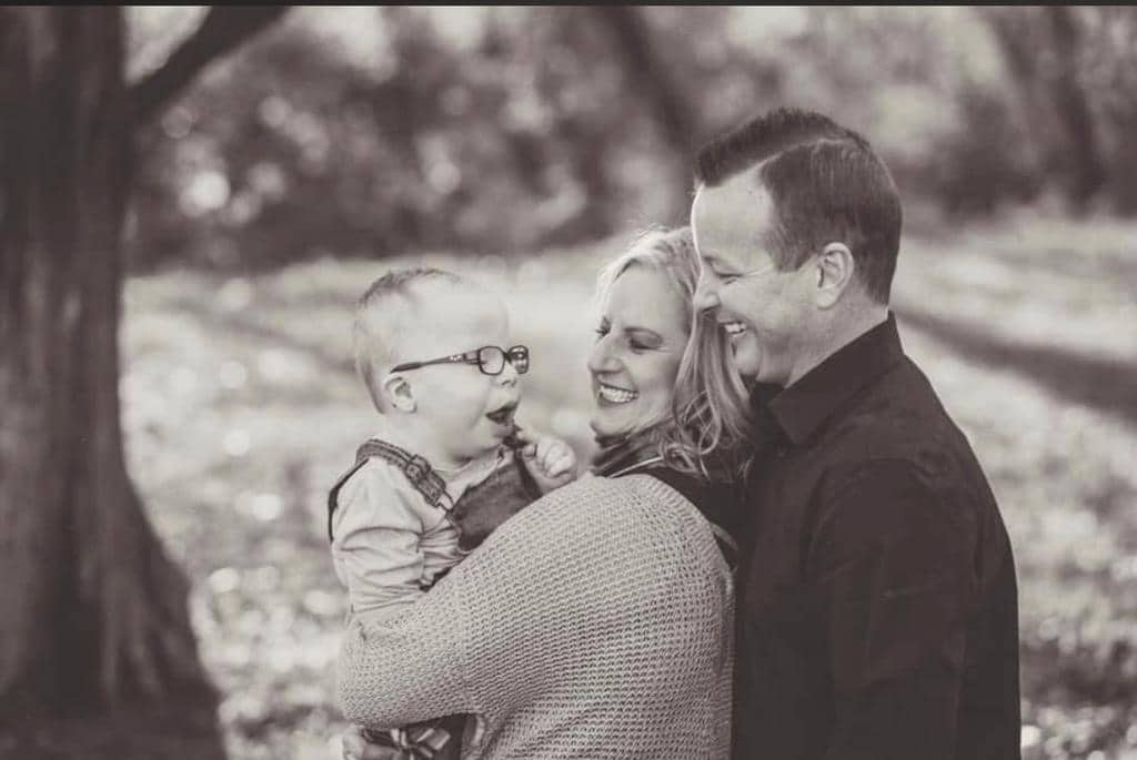 Tim McNutt smiling with his wife Amber and son Elijah, embraced in a moment of joy and strength.